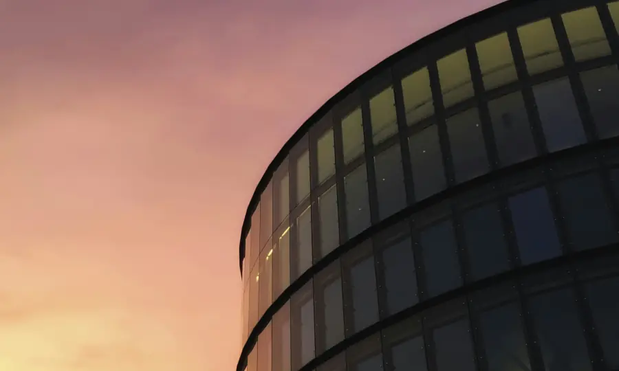 Curved glass office building at sunset